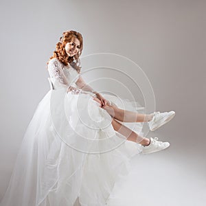 Charming girl in magnificent wedding dress and white sneakers. Runaway bride