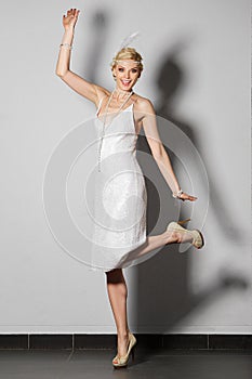 Pretty actress in pearl white retro dress dancing charleston