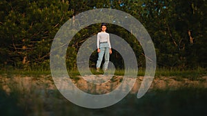 Charming girl among the pine trees in sunset