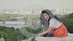 Charming girl relax on plaid in park and feed a doves