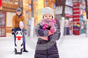 Charming girl on skating rink, dad with little