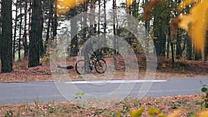 Charming good-looking man in sportswear finished cycling training on road bike at autumn forest and drinking water. Professional m