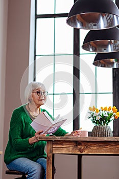 Charming granny responding to someone calling holding book in hand