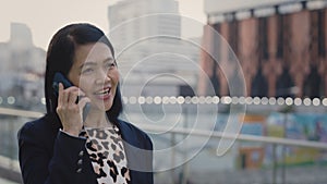 Charming Happy Asian Elderly Lady Walking in the Business District Talking on the Smartphone with Clients.