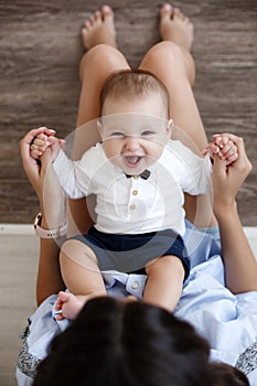 Charming happy little baby boy having fun with mom brunette woman on bed in the bright bedroom