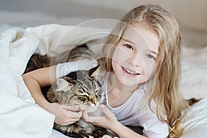 Charming happy little girl hugging her cat