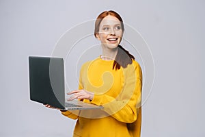 Charming happy young business woman or student holding laptop computer and looking away.