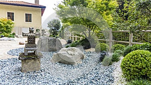 Charming Japanese-style garden with traditional attributes: Oki-gata lantern, gravel paths, boxwood trimmed bushes, maple trees.