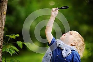 Charming kid exploring nature with magnifying glass