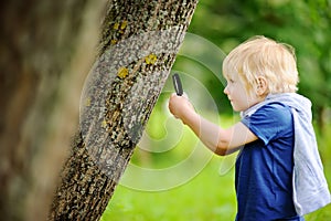 Charming kid exploring nature with magnifying glass