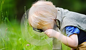 Charming kid exploring nature with magnifying glass