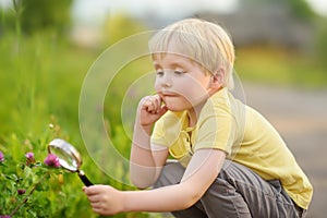 Charming kid exploring nature with magnifying glass