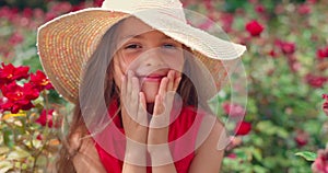 Charming kid, little girl and blooming garden of red roses and spring flowers. Smiling, happy, ashamed woman with hat.