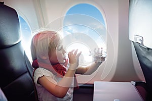 Charming kid traveling by an airplane. Little boy drinking water during the flight