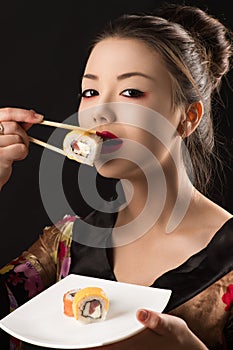 Charming Korean girl eating sushi rolls