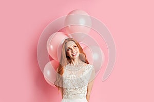 Charming lady looking up with air balloons isolated over pink background