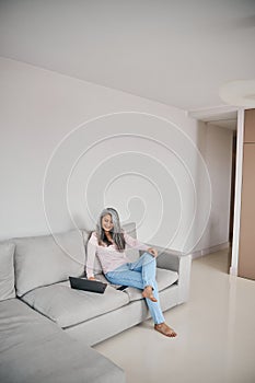 Charming lady spending time at the modern device while surfing internet at home