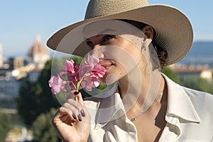 Charming lady stands in a square with stunning views in Florence. Fantastic morning in Italy. Sun hat, flowers, mood of serenity.