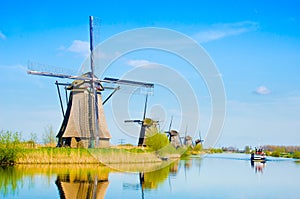 The charming landscape with windmills and boat on river in Kinderdijk, Netherlands, Europe against a background of cloudy sky ref