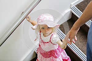 Charming little caucasian girl in pink floral dress looking up , walking downstairs