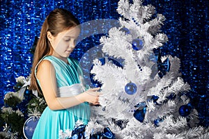 Charming little girl decorates a Christmas tree