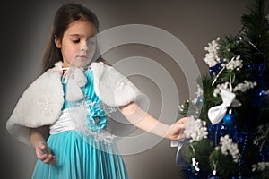 Charming little girl decorates a Christmas tree