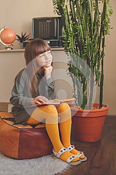 Charming little girl dreaming while reading book