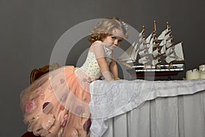 Charming little girl in elegant white with a pink dress sitting