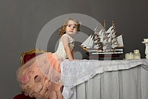 Charming little girl in elegant white with a pink dress sitting