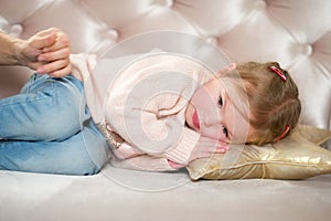 Charming little girl falls asleep on a pink sofa.