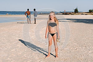 A charming little girl is lying on the beach and drawing on the sand.A little girl lies on the beach of the island of