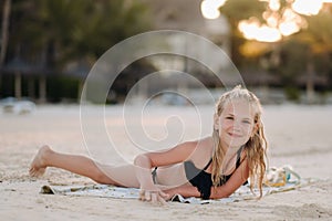 A charming little girl is lying on the beach and drawing on the sand.A little girl lies on the beach of the island of