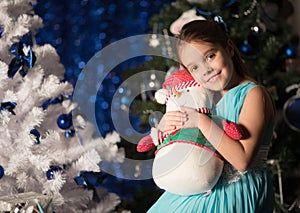 Charming little girl with Pinocchio decorates a Christmas tree