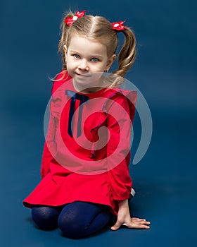 Charming little girl in red dress sitting on knees