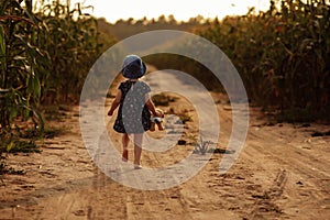 Charming little girl runs along a field road.