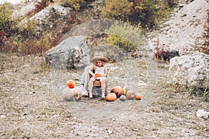 Charming little girl in a straw hat, wicker chair, pumpkins