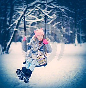 Charming little girl on swing in snowy winter