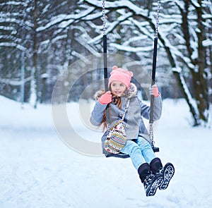 Charming little girl on swing in snowy winter