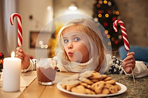 Charming little girl with two candy canes while having festive