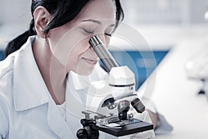 Charming mature lady examining sample under microscope