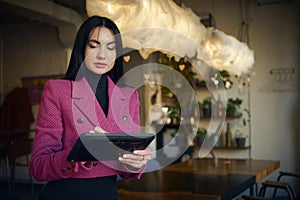 Charming middle-aged woman, restaurateur, CEO, manager, business lady working on tablet in modern restaurant interior