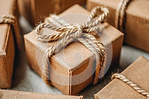 Close-up of neatly wrapped small gift boxes in brown paper tied with rustic natural rope bows arranged on a soft textured surface