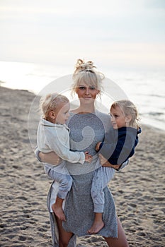 Charming mom carrying her beloved twin sons - summer shot