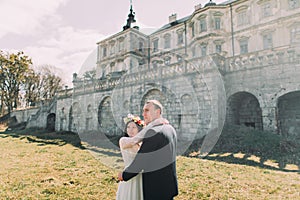 Charming newlywed bride and groom walking near beautiful ruined baroque palace