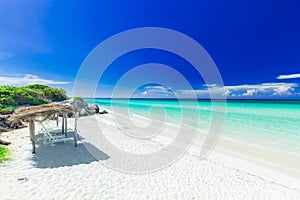 Charming nviting view of tropical white sand beach and tranquil turquoise tender ocean on dark deep, blue sky background