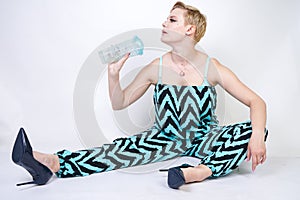 Charming plus size young woman in black blue jumpsuit with glass of water on white background in Studio. pretty blonde girl wearin