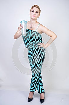 Charming plus size young woman in black blue jumpsuit with glass of water on white background in Studio. pretty blonde girl wearin