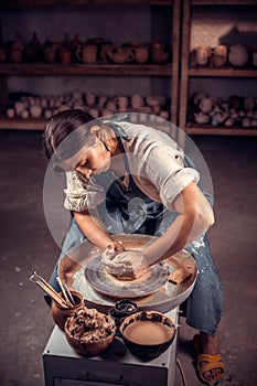 Charming potter female student shows how to work with clay and pottery wheel. Handwork.