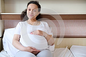 Charming pregnant woman stroking big baby bump, enjoying future motherhood, relation, contact with her child, pregnancy