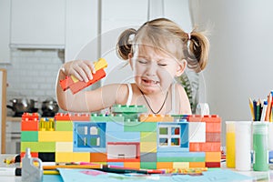 Charming preschooler playing with doll house constructor. Little girl playing with connecting toy cubes